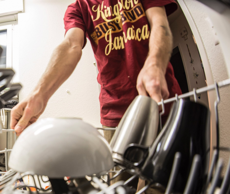 Home appliance repair: a young man loading a dishwasher